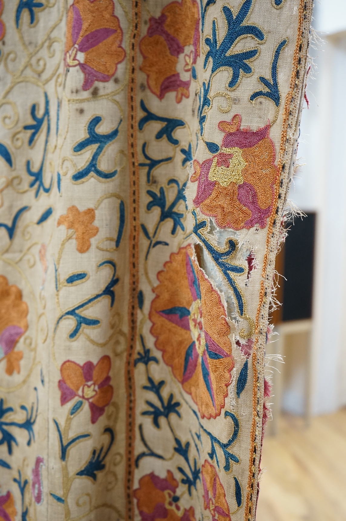A 19th century, circa 1850-1880 hand embroidered Suzani wall hanging, probably from Uzbekistan. Worked on had woven linen, predominantly embroidered in orange, ochre, maroon and green silks in fine chain stitch with an o